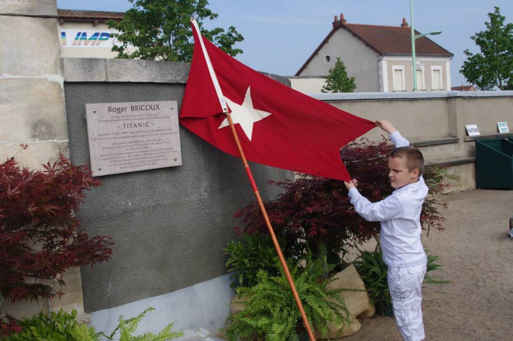 Un enfant brandit le drapeau de l'AFT devant la plaque