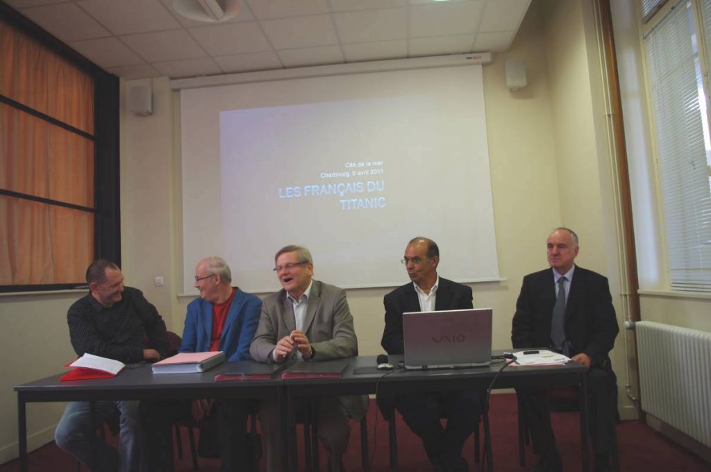Cinq hommes à la tribune devant un écran