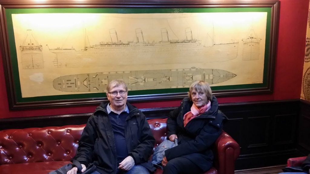 Deux personnes posent dans un canapé devant un plan du Titanic.