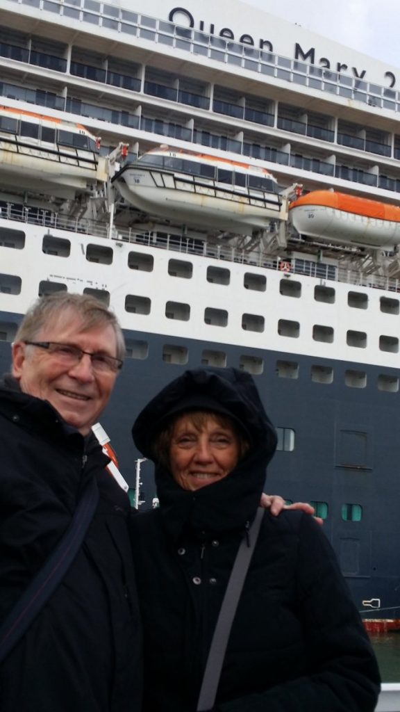 Deux personnes posent devant le Queen Mary 2.