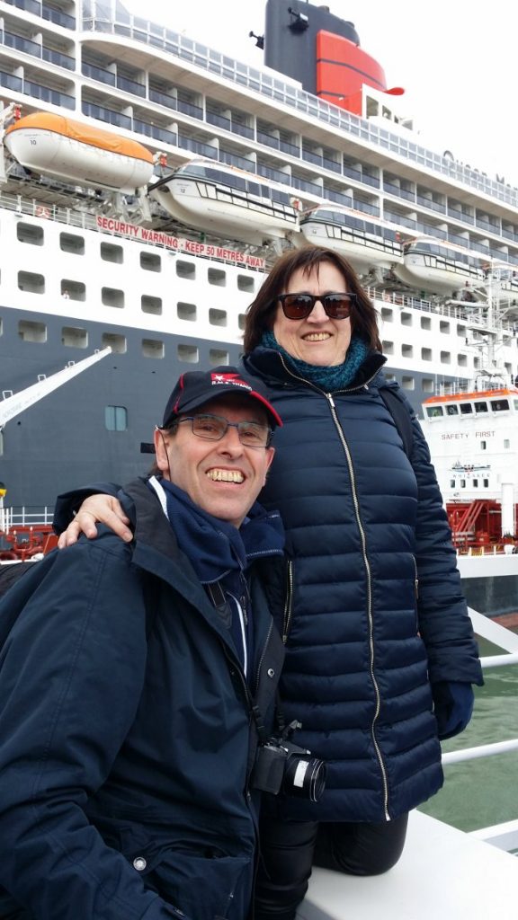 Deux personnes posent devant le Queen Mary 2.