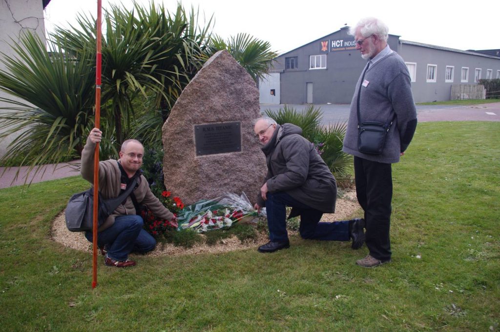 Trois hommes posent des fleurs sur la stèle en hommage au Titanic