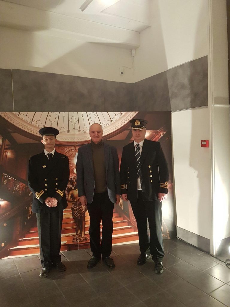 Trois personnes posent devant la photo du Grand escalier.