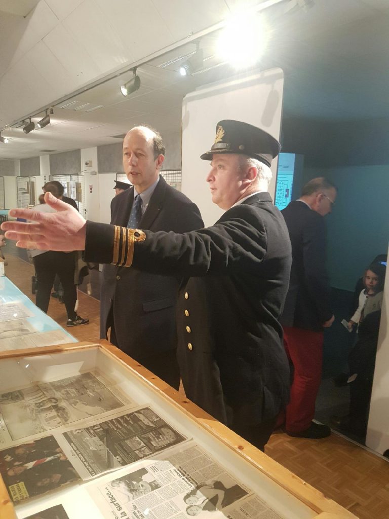 Un homme habillé en officier présente une vitrine au Maire.