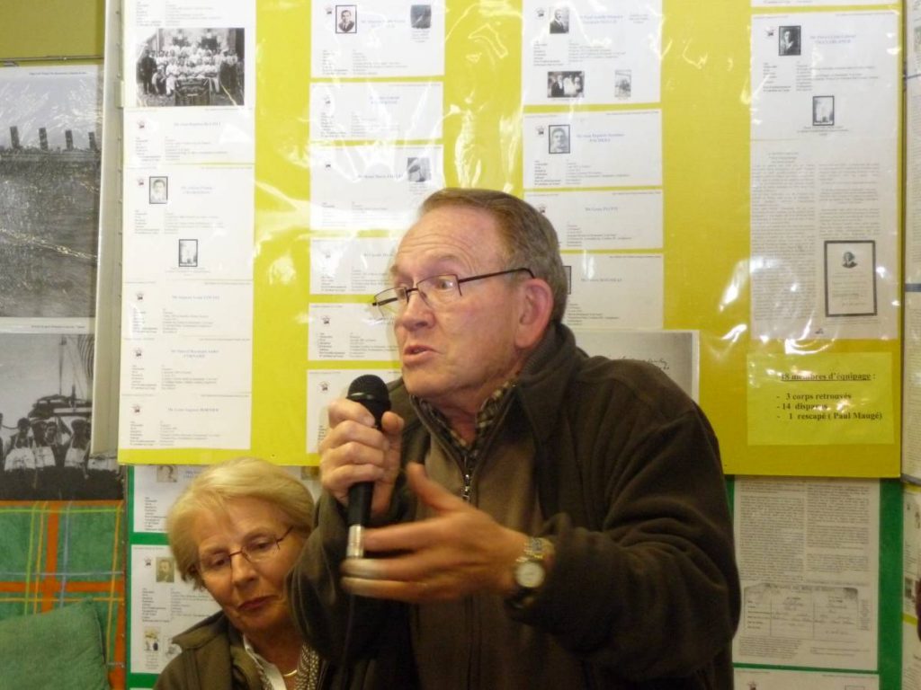 Un homme parle au micro devant les panneaux d'exposition