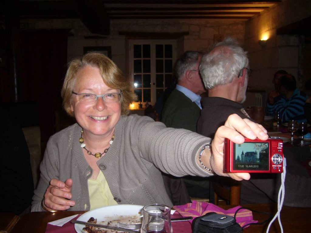 Une femme à table montre son appareil photo.