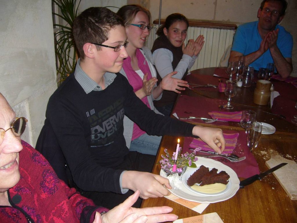 Plusieurs personnes devant un gâteau à table.