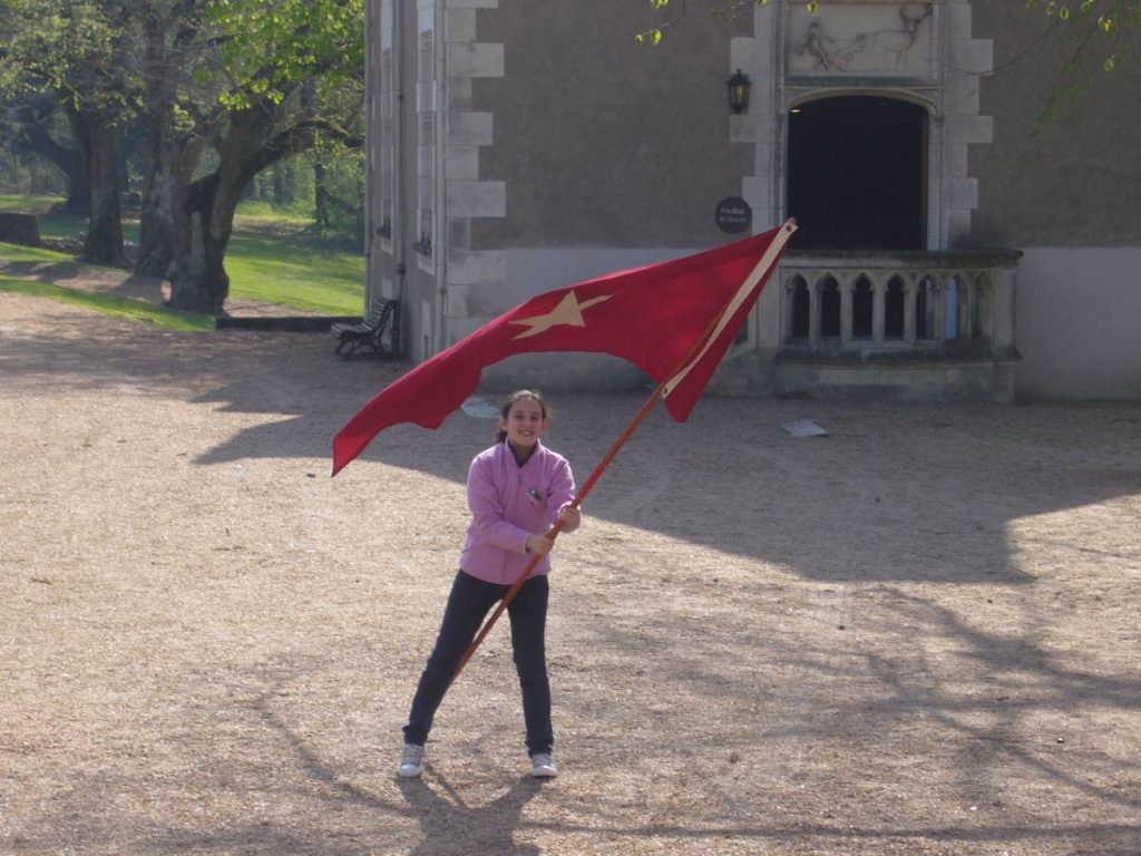 Une fille brandit un drapeau rouge à étoile blanche.