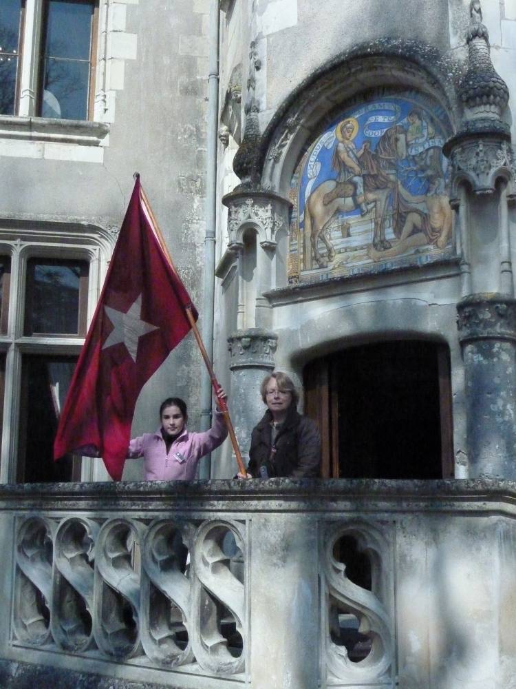Deux personnes posent sur un balcon à côté du drapeau de l'AFT.