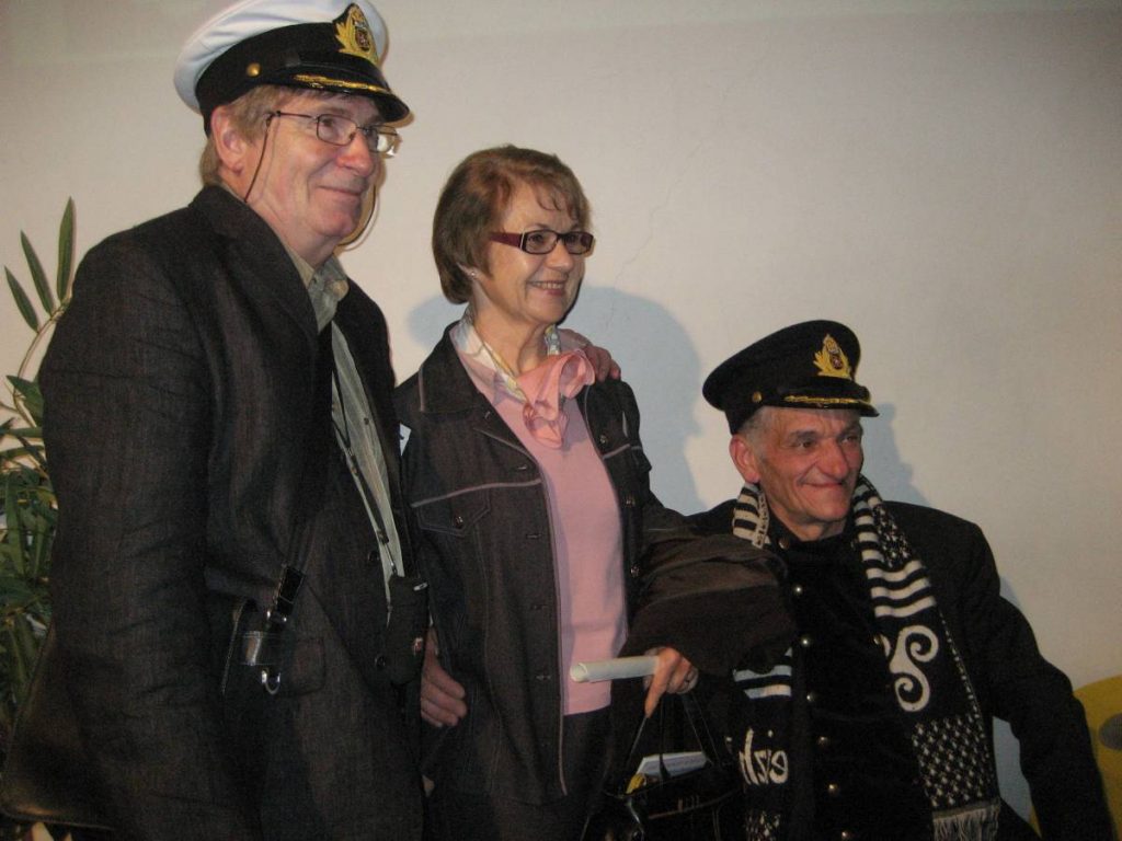 Deux hommes posent avec une casquette d'officier autour d'une femme.