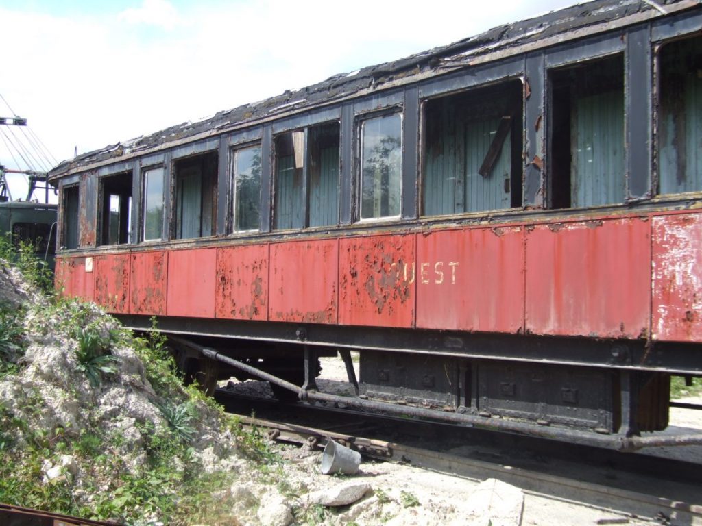 Vue du wagon rouge et noir dans un état de délabrement avancé.