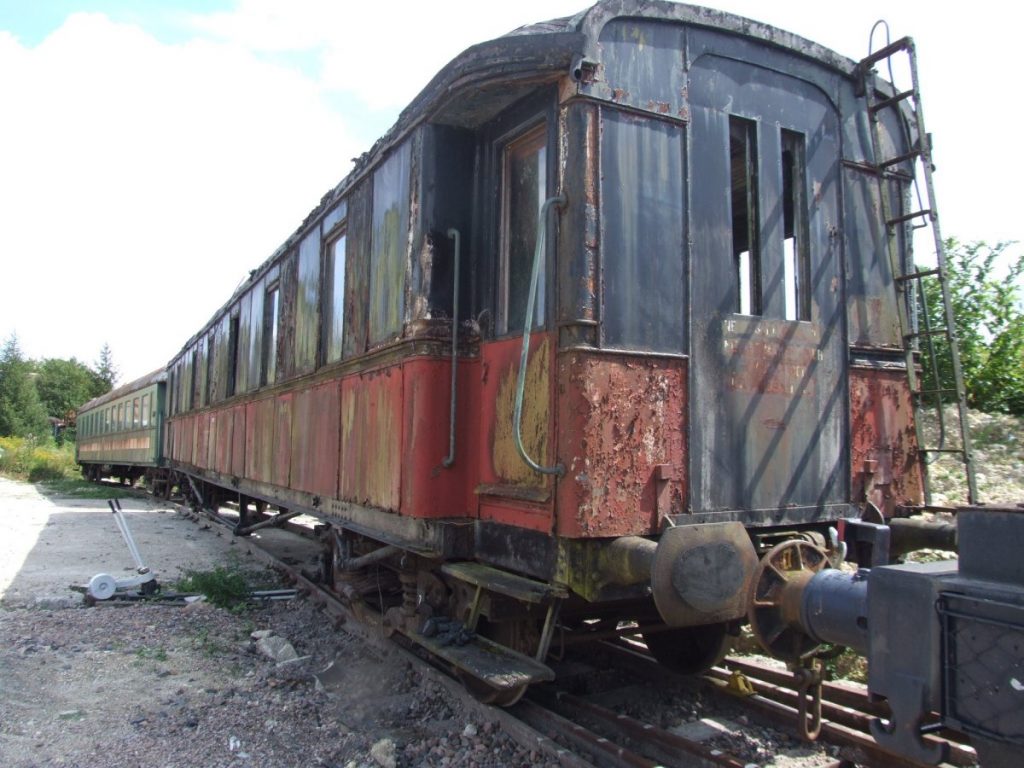 Vue du wagon rouge et noir dans un état de délabrement avancé.
