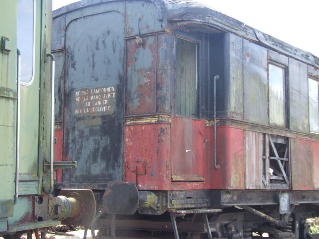 Vue du wagon rouge et noir dans un état de délabrement avancé.