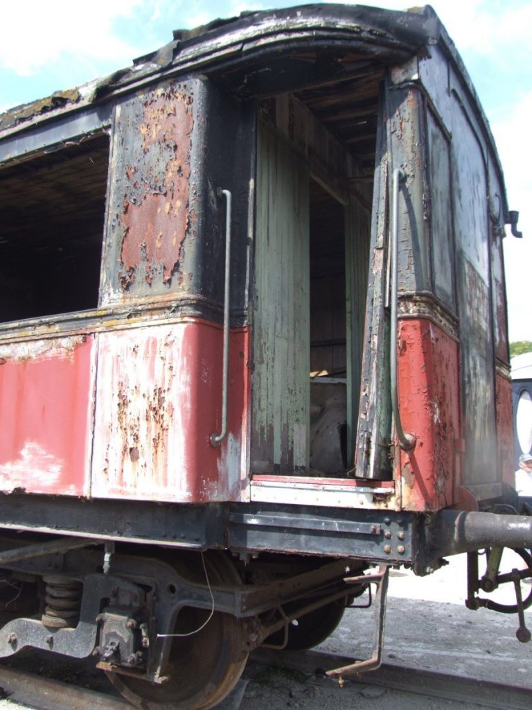 Vue du wagon rouge et noir dans un état de délabrement avancé.