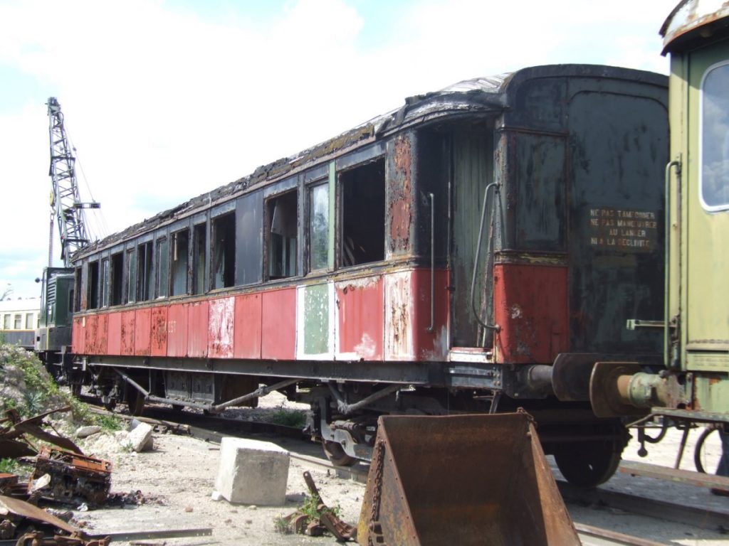 Vue du wagon rouge et noir dans un état de délabrement avancé.
