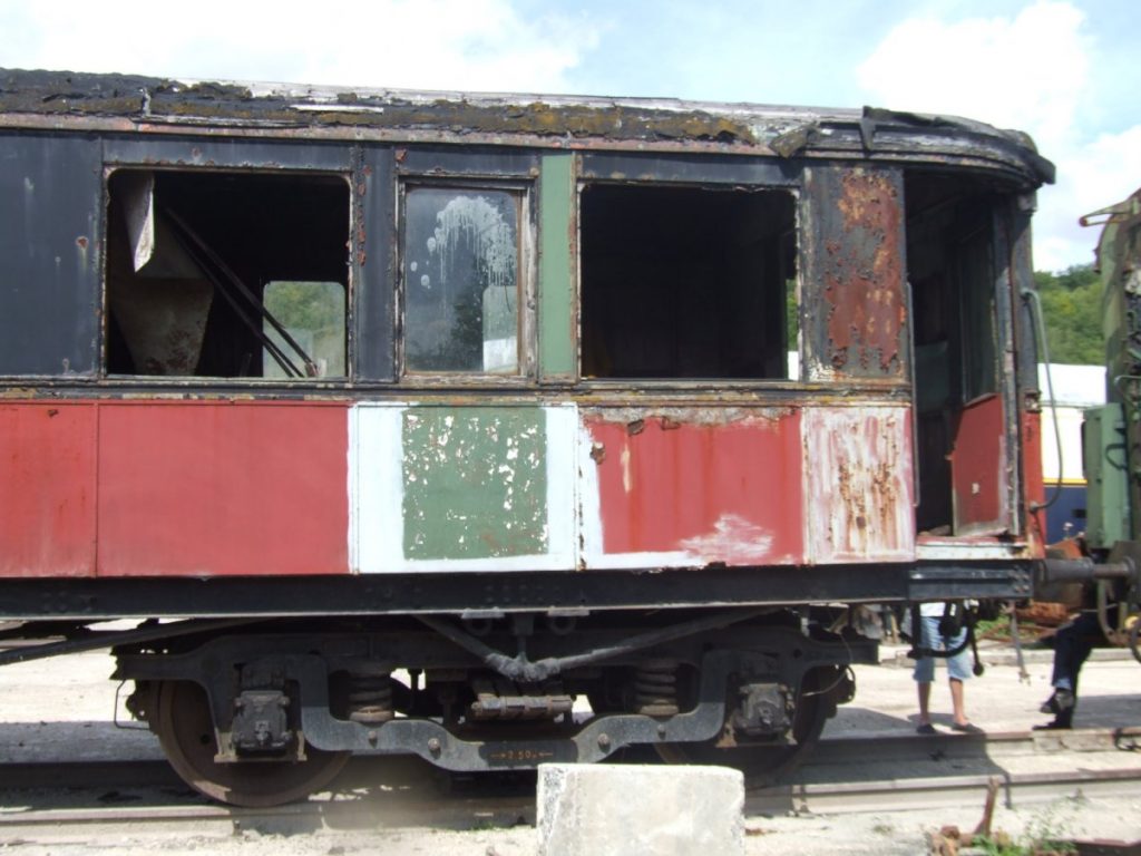 Vue du wagon rouge et noir dans un état de délabrement avancé.