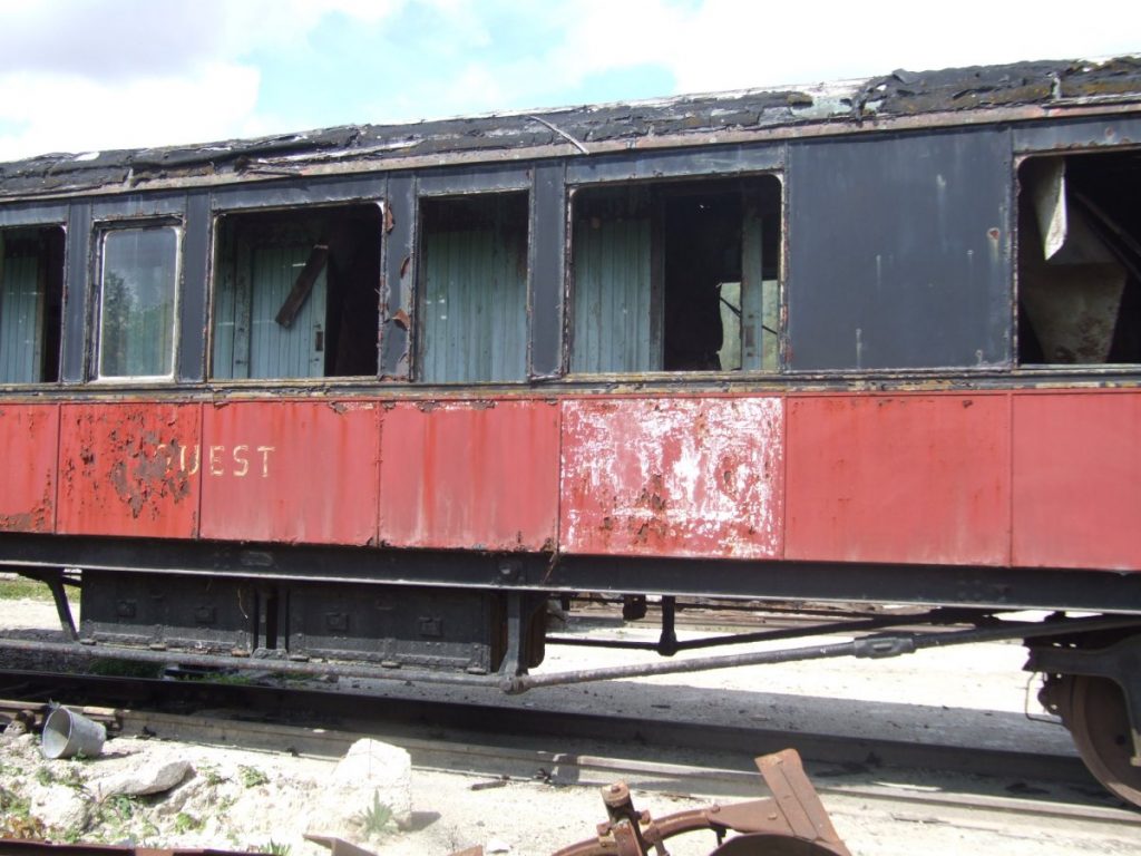 Vue du wagon rouge et noir dans un état de délabrement avancé.