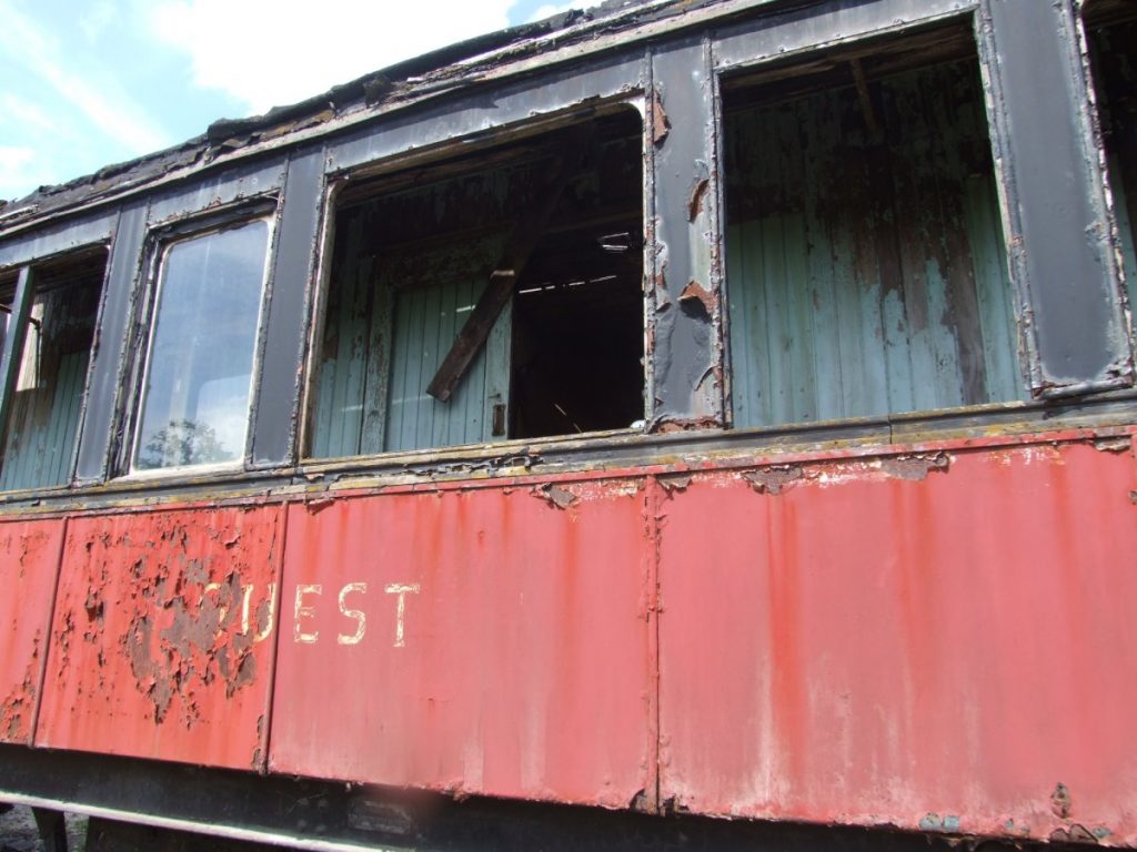 Vue du wagon rouge et noir dans un état de délabrement avancé.