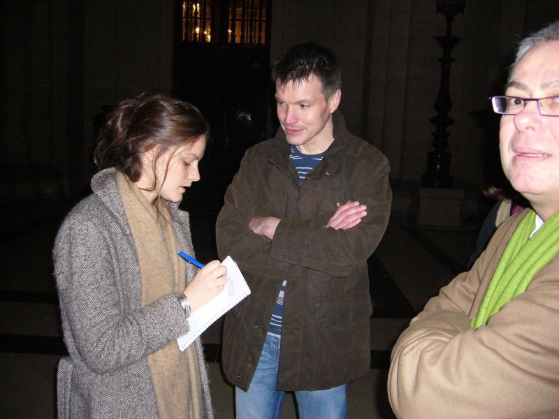 Un homme répond à une journaliste prenant des notes.