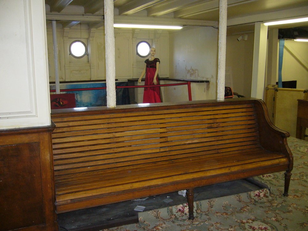 Banc et, en arrière plan, un mannequin portant une robe d'époque.