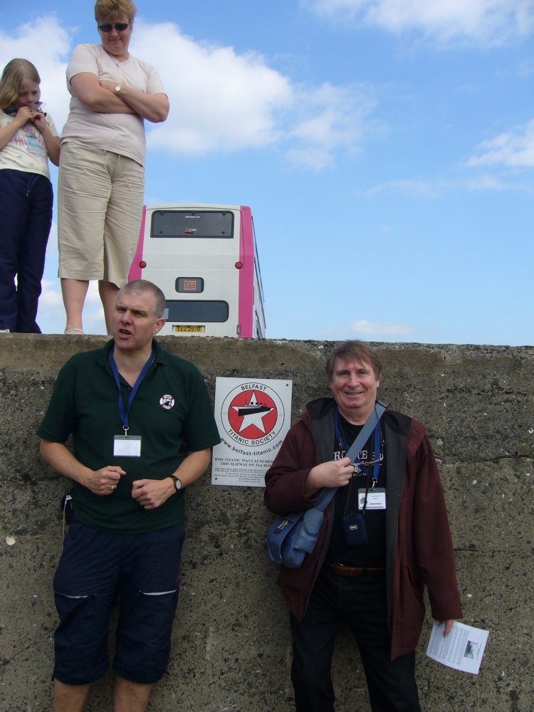 Deux hommes posent à côté d'une plaque de la Belfast Titanic Society.
